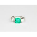 A platinum ring set with an emerald cut emerald and baguette cut diamond set shoulders, approx. 2.