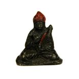 A Tibetan cast bronze temple figure of a seated lama with remnants of red colouring, H. 6cm.