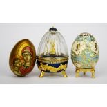 A Russian painted wooden egg icon and a two Russian style enamelled egg boxes, tallest 9cm.