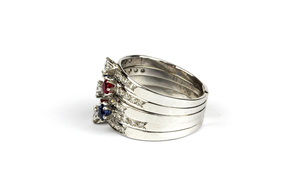 A white metal (tested 18ct gold) ring set with brilliant cut diamonds, rubies and sapphires, (O). - Image 2 of 2