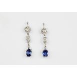 A pair of white metal (tested high carat gold) drop earrings set with oval cut sapphires and