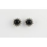 A pair of white metal (tested 18ct gold) cluster earrings set with cabochon cut star black sapphires
