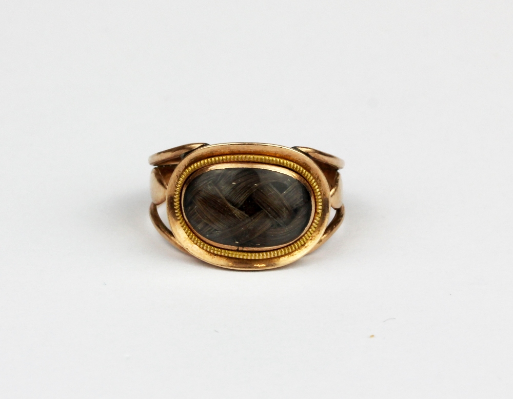 A gilt metal (tested minimum 9ct gold) mourning ring with an oval shaped hair compartment, (J).