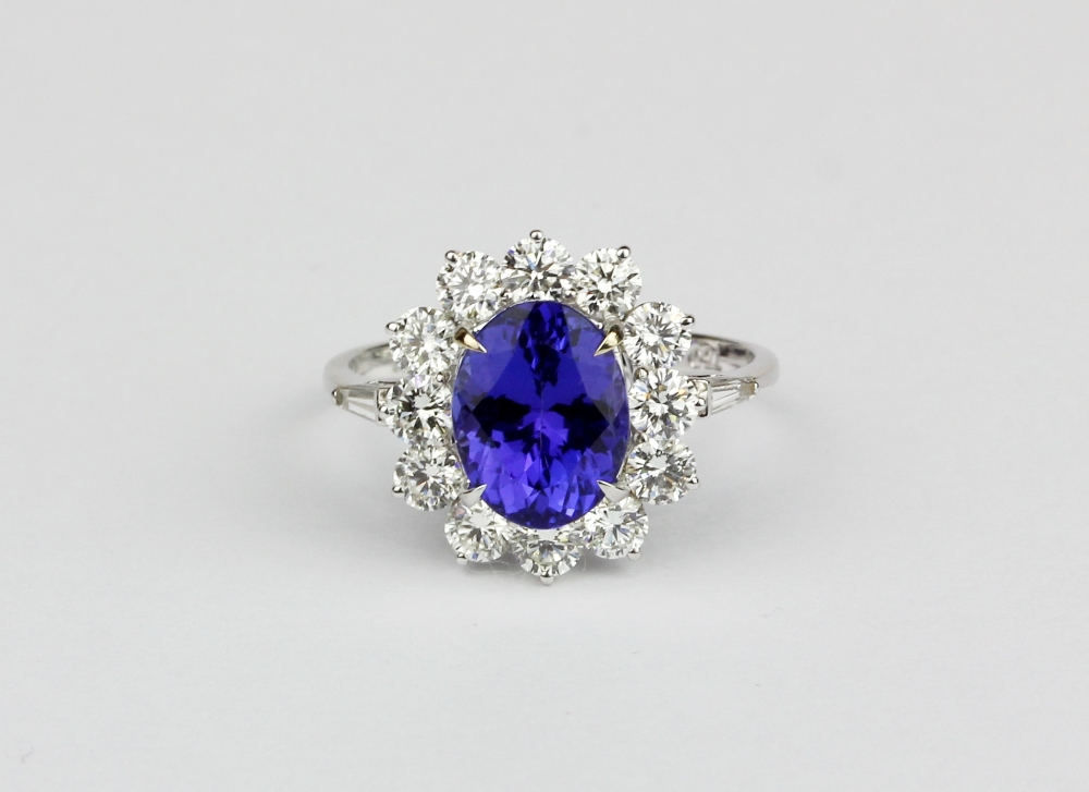 An 18ct white gold (stamped 750) cluster ring set with an oval cut tanzanite surrounded by brilliant