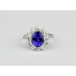 An 18ct white gold (stamped 750) cluster ring set with an oval cut tanzanite surrounded by brilliant