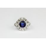 A white metal (tested high carat gold) ring set with a cushion cut sapphire surrounded by cut