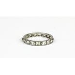 A white metal (tested platinum) eternity ring set with old oval cut diamonds, (M.5).