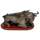 A Chinese bronze coloured terracotta figure of a water buffalo on a wooden pedestal, L. 46cm.