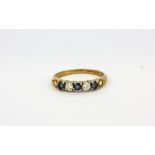 A 9ct yellow gold sapphire and white stone set half eternity ring, (L.5).