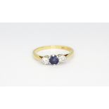 An 18ct yellow gold and platinum ring set with a sapphire flanked by brilliant cut diamonds, (L).