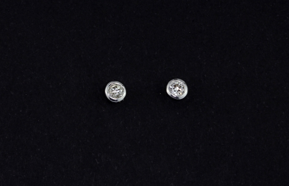 A pair of 9ct white gold (stamped 375) rub over set brilliant cut diamond stud earrings, approx. 0.