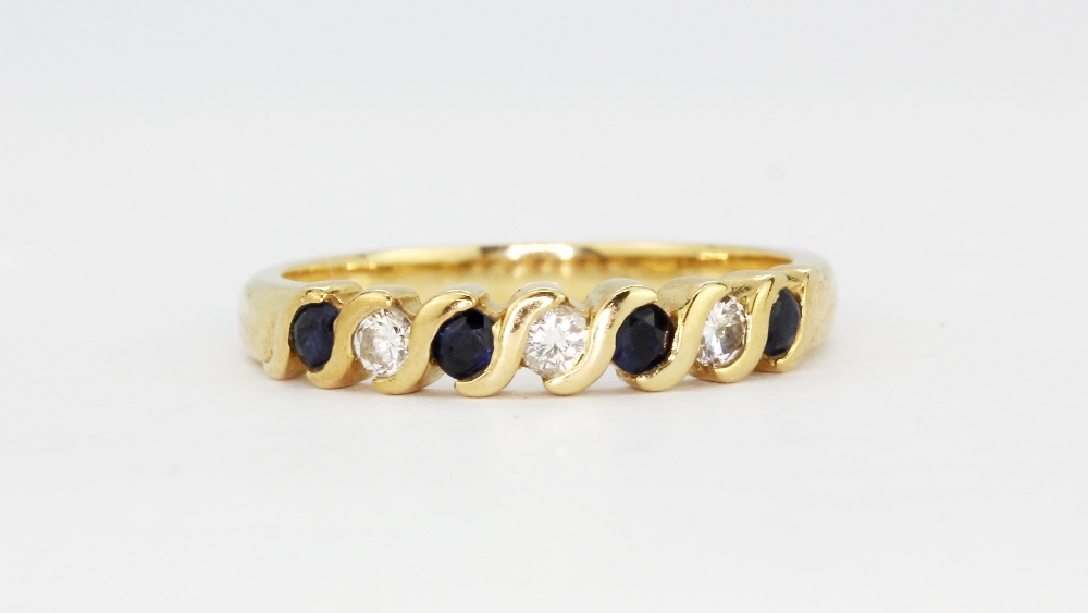 A 14ct yellow gold (stamped 14k) half eternity ring set with sapphires and brilliant cut