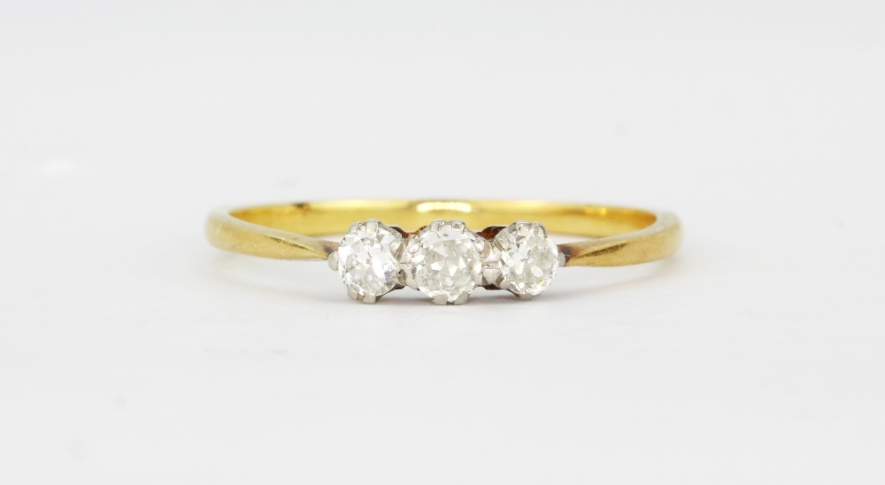 A yellow metal (tested 18ct gold) ring set with three old brilliant cut diamonds, (N.5).