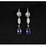 A pair of white metal (tested minimum 9ct gold) drop earrings set with oval cut sapphires and