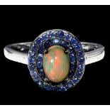 A 925 silver cluster ring set with cabochon cut opal and two rows of sapphires, (O).