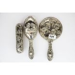 A three piece hallmarked silver cherub pattern dressing table set.