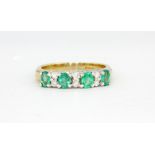 A hallmarked 9ct yellow and white gold ring set with oval cut emeralds and brilliant cut