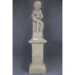 A reconstituted stone resin figure of a child reading a book, with pedestal H. 75cm.