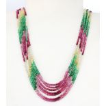 A seven strand necklace of cut semi-precious stones including emeralds, rubies, citrines and white