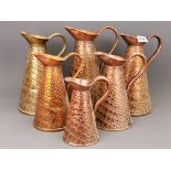 A graduated set of five 19th century hammered copper jugs and one matching brass jug tallest H.