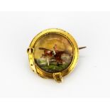 An antique yellow metal (tested gold) hand painted brooch depicting a jockey and horse, Dia.2.2cms
