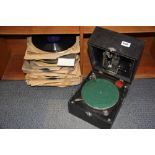 An early portable wind up gramophone with a quantity of 78RPM records.