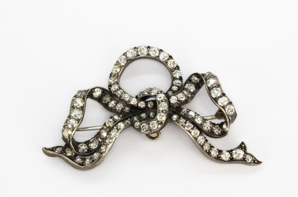 An antique white metal (tested high carat gold) bow shaped brooch set with old cut diamonds in a