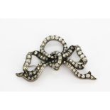 An antique white metal (tested high carat gold) bow shaped brooch set with old cut diamonds in a