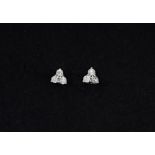 A pair of white metal (tested 18ct gold) stud earrings each set with three brilliant cut diamonds,