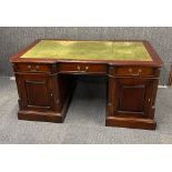 A leather top mahogany partners desk with nine drawers on one side and three drawers and two