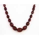 A single strand graduated necklace of old faceted cherry amber beads on a yellow metal tested 9ct