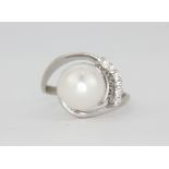 A white metal (tested 18ct gold) ring set with a large cultured 10mm pearl and brilliant cut