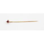 A boxed yellow metal (tested minimum 9ct gold) stick pin set with an oval cut ruby and brilliant cut