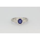 A hallmarked white gold ring set with an oval cut sapphire and brilliant cut diamonds, (M.5).