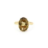 A hallmarked 9ct yellow gold ring set with a large oval cut smokey quartz, (Q). L.1.3cm.