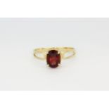 A 10ct yellow gold (stamped 10k) solitaire ring set with an oval cut garnet, (N.5).