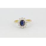 A hallmarked 18ct yellow gold sapphire set cluster ring surrounded by brilliant cut diamonds, (L).