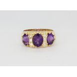 A hallmarked 9ct yellow gold ring set with three large oval cut amethysts and bright old cut