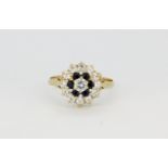 A hallmarked 9ct yellow gold cluster ring set with sapphires and white stones, (N.5).