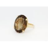 A 14ct yellow gold (stamped 14k) ring set with a large oval cut smokey quartz, (M).