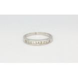 A white metal (tested minimum 9ct gold) half eternity ring set with princess cut diamonds, (L.5).