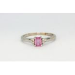 A 14ct white gold (stamped 14k) solitaire ring set with an emerald cut pink sapphire and diamond set