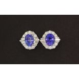 A pair of 18ct white gold stud earrings set with an oval cut tanzanite surrounded by diamonds,