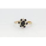 A 9ct yellow gold (stamped 9k) cluster ring set with an oval cut sapphire surrounded by diamonds and