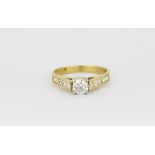 An 18ct yellow gold ring set with a brilliant cut diamond and diamond set shoulders, approx. 0.45