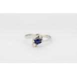 An 18ct white gold (stamped 750) crossover ring set with a marquise cut sapphire and brilliant cut