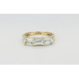 A 14ct yellow gold (stamped 14k) ring set with three emerald cut aquamarines, (M).