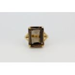 A 10ct yellow gold (stamped 10k) open shoulder ring set with a large emerald cut smokey quartz, (