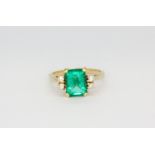 A 14ct yellow gold (stamped 14k) ring set with a large emerald cut emerald and brilliant cut