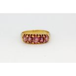 A hallmarked 18ct yellow gold ring set with cushion cut pink tourmalines, (O.5).